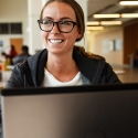 Student smiling looking over computer screen